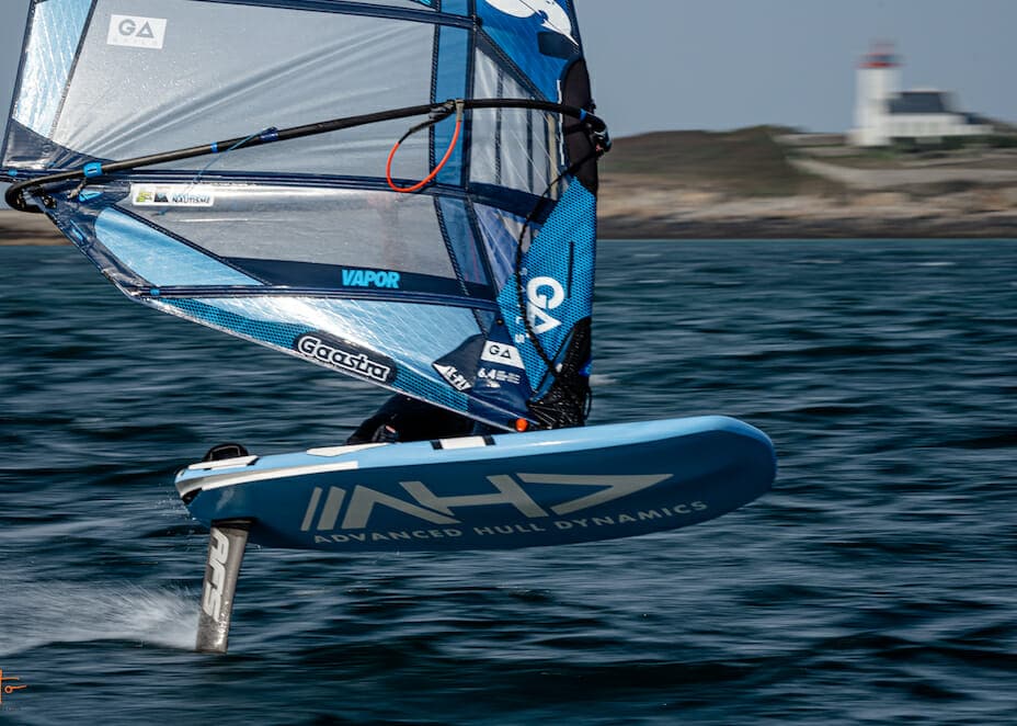 Un homme fait de la planche à voile dans l'océan avec une voile.